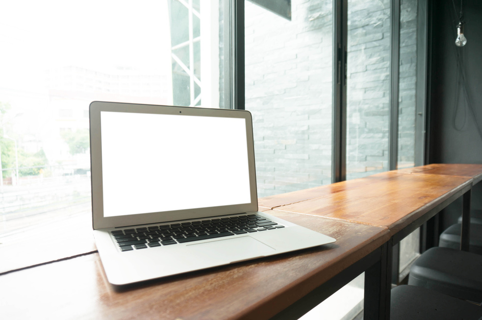 Laptop with Blank Screen on Wooden Table in Front of Office Wind